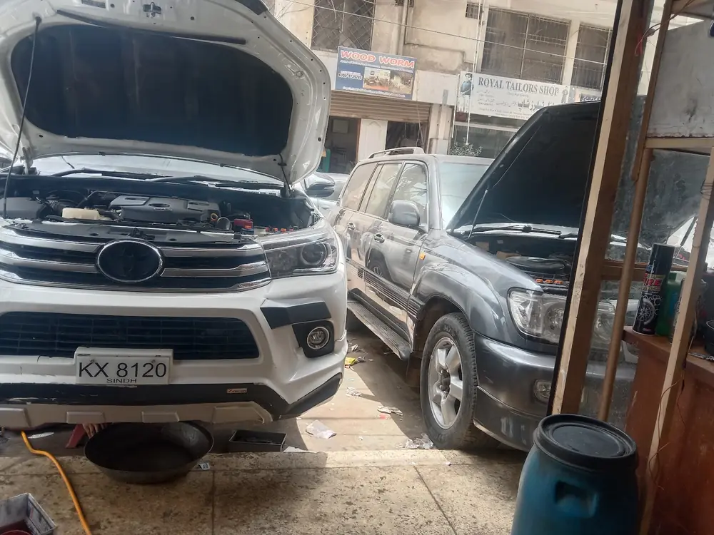 Two SUVs with bonnets open outside Mian Autos
